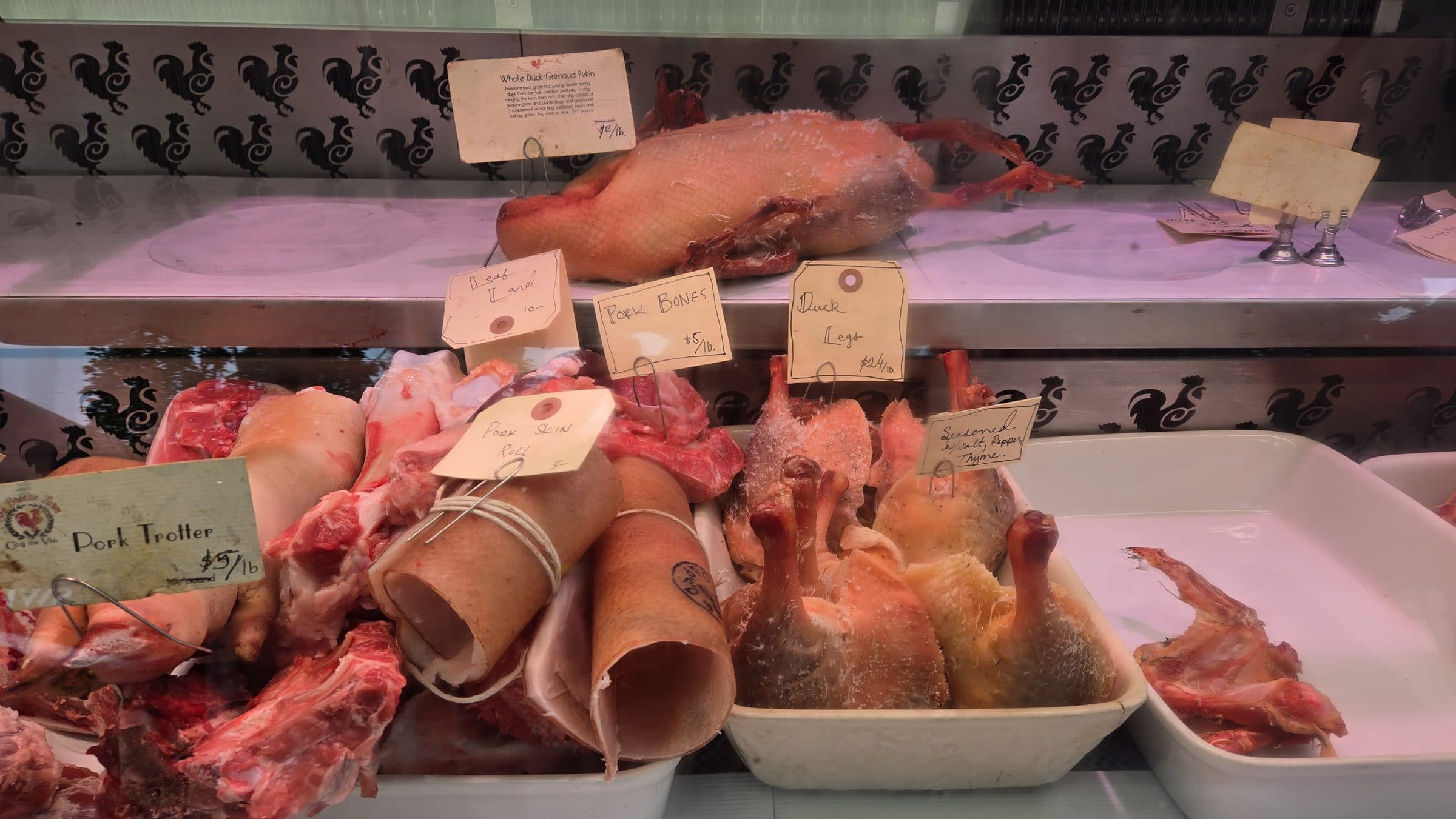 Whole duck, duck legs, and pork cuts in the Sea Breeze Farm market case