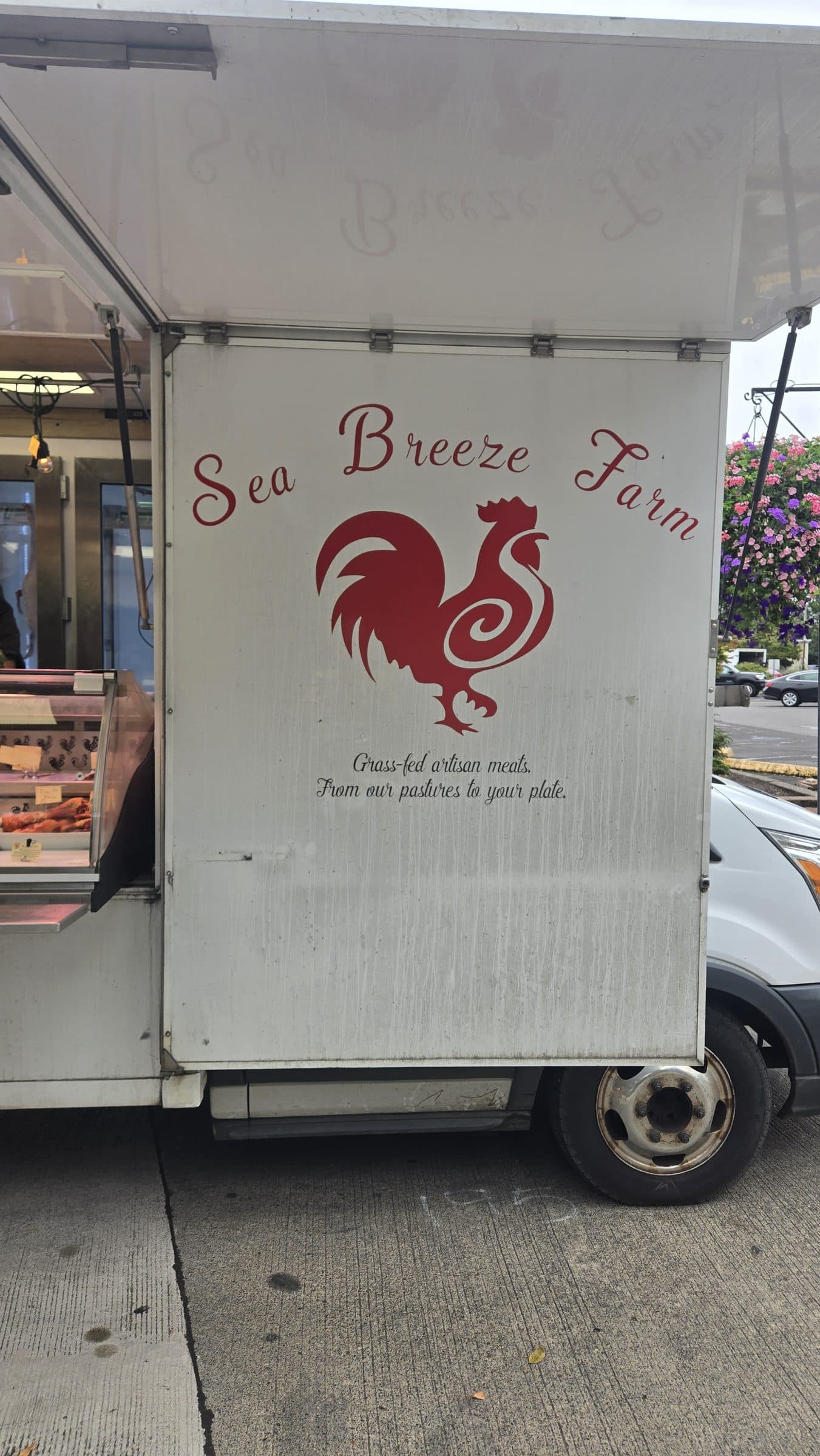 Sea Breeze Farm market trailer with a red rooster logo and the line Grass-fed artisan meats